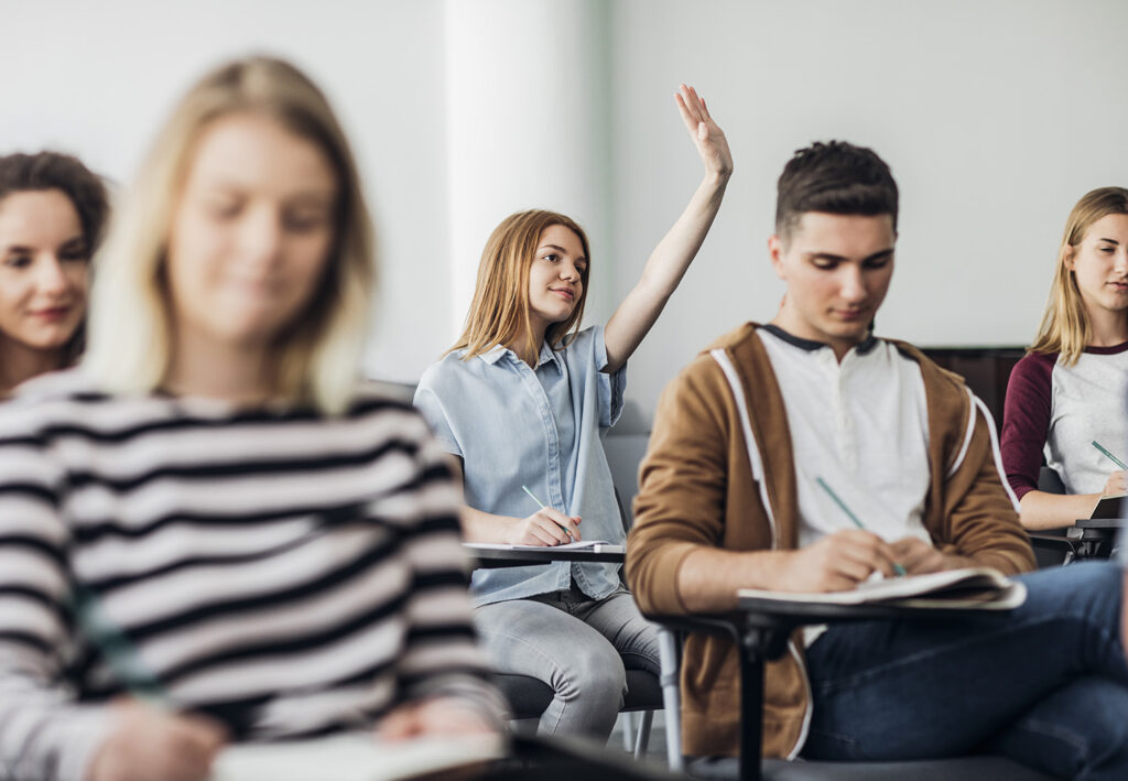 Photo of a teenage student raising hand in class